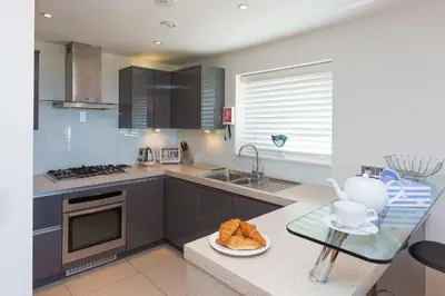 a kitchen with a sink and a counter with a table at Carbis Sands in Carbis Bay