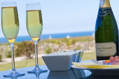 two glasses of champagne on a table with a bottle of wine at Carbis Sands in Carbis Bay