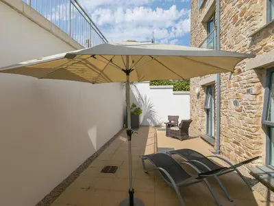 a patio with two chairs and an umbrella at Carbis Sands in Carbis Bay