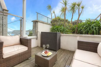 a balcony with two chairs and a table with wine glasses at Serendipity in St Ives