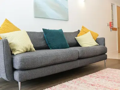 a gray couch with colorful pillows on it in a living room at Serendipity in St Ives