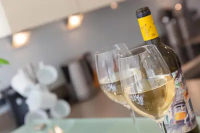 a bottle of white wine next to two wine glasses at Tides in St Ives