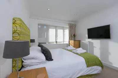 a bedroom with a bed with a television on the wall at Tides in St Ives