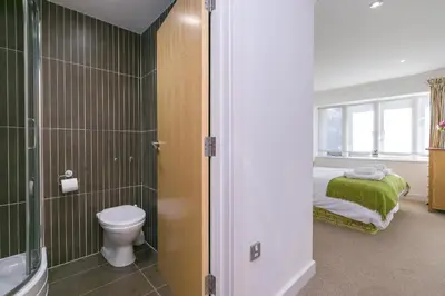 a bathroom with a toilet and a bed and a window at Tides in St Ives
