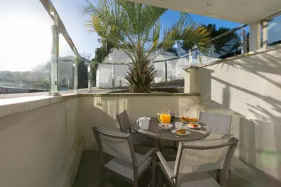 a table and chairs on a balcony with a table and drinks at Tides in St Ives