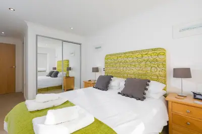 a bedroom with a large bed and a mirror at Tides in St Ives
