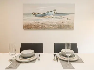 a table with plates and glasses and a painting of a boat at Bluebell Retreat in Lostwithiel