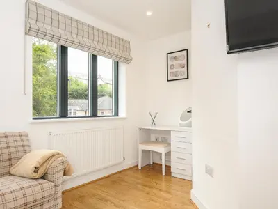 a living room with a chair and a window at Bluebell Retreat in Lostwithiel