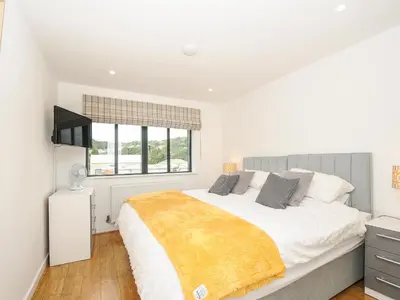 a white bedroom with a large bed and a window at Bluebell Retreat in Lostwithiel
