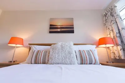 a bedroom with a white bed with two lamps at Sowena in Carbis Bay