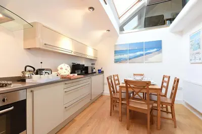 a kitchen with a table and chairs and a skylight at The Sail Loft in St Ives