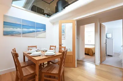 a dining room with a table and chairs and a bedroom at The Sail Loft in St Ives