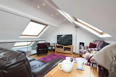 a living room with a couch and a tv at The Sail Loft in St Ives