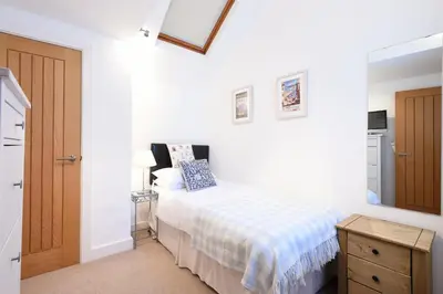 a bedroom with a bed with a blue and white blanket at The Sail Loft in St Ives
