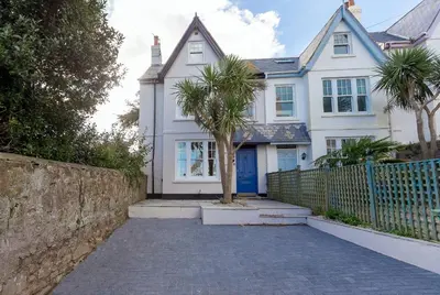a white house with a palm tree in front of it at Sea Dream in St Ives