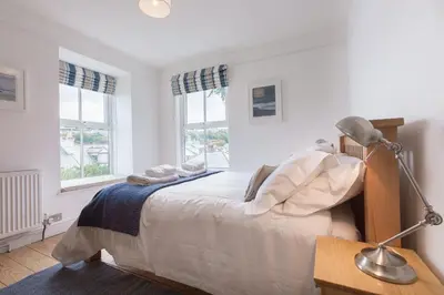 a bedroom with a bed with a lamp and two windows at Sea Dream in St Ives