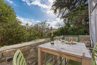 a wooden table with a bottle of wine and wine glasses at Sea Dream in St Ives