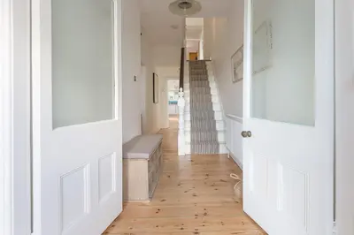 a hallway with white doors and wooden floors at Sea Dream in St Ives