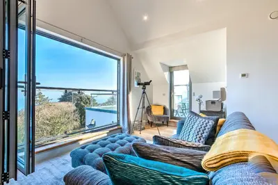 a living room with a blue couch and a large window at Sea Vista in Carbis Bay