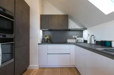 a kitchen with white cabinets and stainless steel appliances at Sea Vista in Carbis Bay