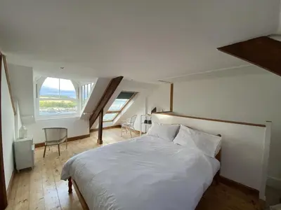 a bedroom with a white bed and a large window at Frobisher Apartments in Falmouth