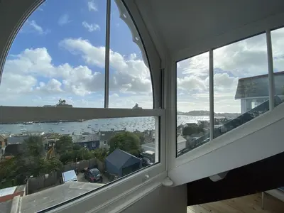 an arched window with a view of the water at Frobisher Apartments in Falmouth