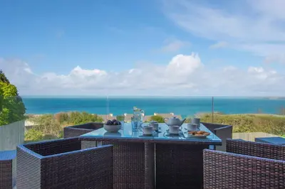 a table with food on top of a balcony with the ocean at Halcyon Cove in Carbis Bay