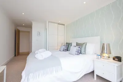 a bedroom with a large white bed and a night stand at Halcyon Cove in Carbis Bay