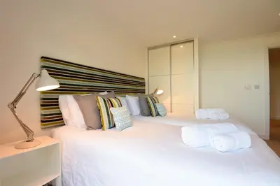 a bedroom with a large white bed with towels on it at Halcyon Cove in Carbis Bay