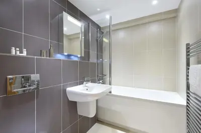 a white bathroom with a sink and a mirror at Halcyon Cove in Carbis Bay