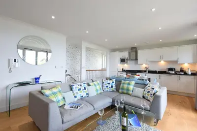a living room with a couch and a kitchen at Halcyon Cove in Carbis Bay