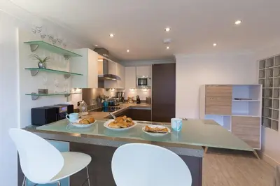 a kitchen with two white chairs and a counter with food on it at The Sanctuary in St Ives