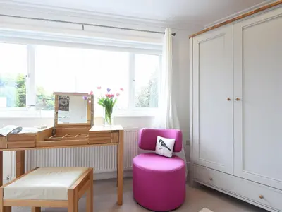 a pink chair in front of a desk with a mirror at Shamal in Carbis Bay