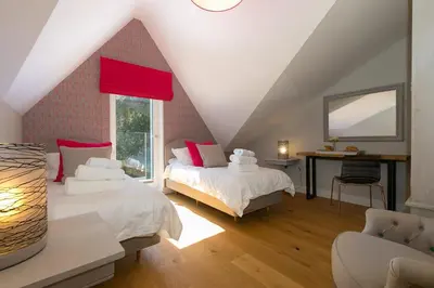 a attic bedroom with two beds and a desk at The Oyster in St Ives