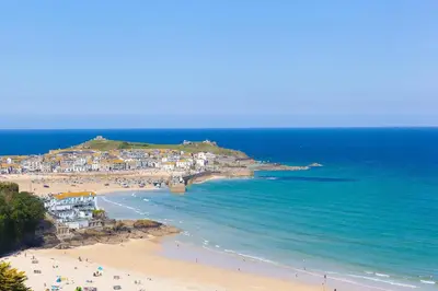 a beach with people on the sand and the ocean at The Pearl in St Ives