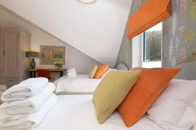 a bedroom with two beds with white sheets and orange pillows at The Pearl in St Ives
