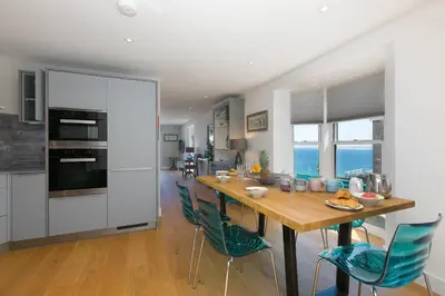 a kitchen and dining room with a wooden table and chairs at The Pearl in St Ives