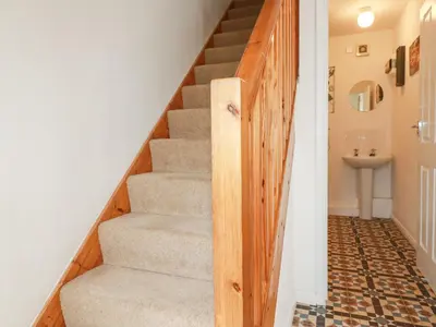 a staircase with a wooden door leading to a bathroom at 2 Old Talbot Cottages in Lostwithiel