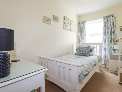 a white bedroom with a bed and a window at 2 Old Talbot Cottages in Lostwithiel
