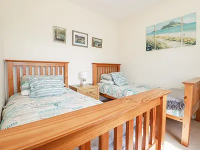 a bedroom with two beds and a wooden rail at 2 Old Talbot Cottages in Lostwithiel