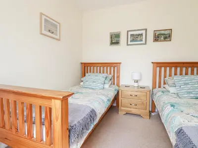 a bedroom with two twin beds and a night stand at 2 Old Talbot Cottages in Lostwithiel