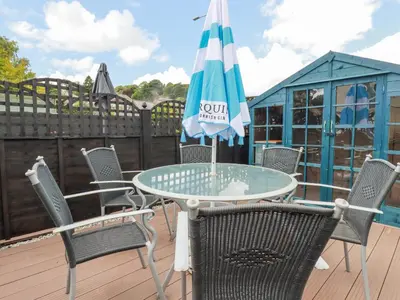 a table and chairs with an umbrella on a deck at 2 Old Talbot Cottages in Lostwithiel