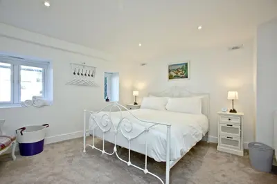 a white bedroom with a white bed and a window at Charming Cottage, Wi-Fi, Parking, Pets Accepted in Newquay