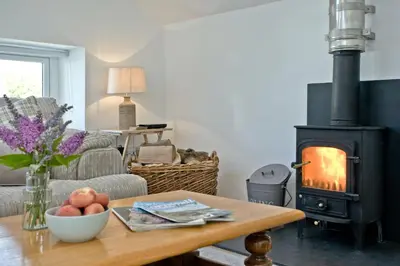 a living room with a wood stove and a table at Charming Cottage, Wi-Fi, Parking, Pets Accepted in Newquay