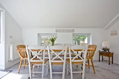 a white dining room with a table and chairs at Charming Cottage, Wi-Fi, Parking, Pets Accepted in Newquay