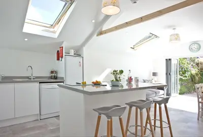 a kitchen with white cabinets and a counter with stools at Charming Cottage, Wi-Fi, Parking, Pets Accepted in Newquay