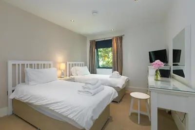 a bedroom with two beds and a desk and a window at Waters Edge in St Ives