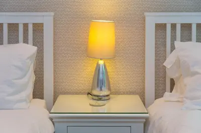 a lamp on a night stand next to two beds at Waters Edge in St Ives