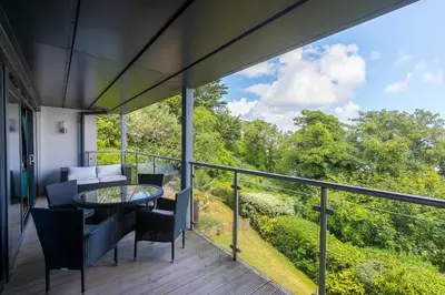 a patio with a table and chairs on a balcony at Waters Edge in St Ives