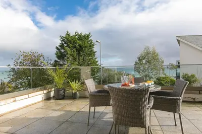 a patio with a table and chairs and the ocean at The View in St Ives
